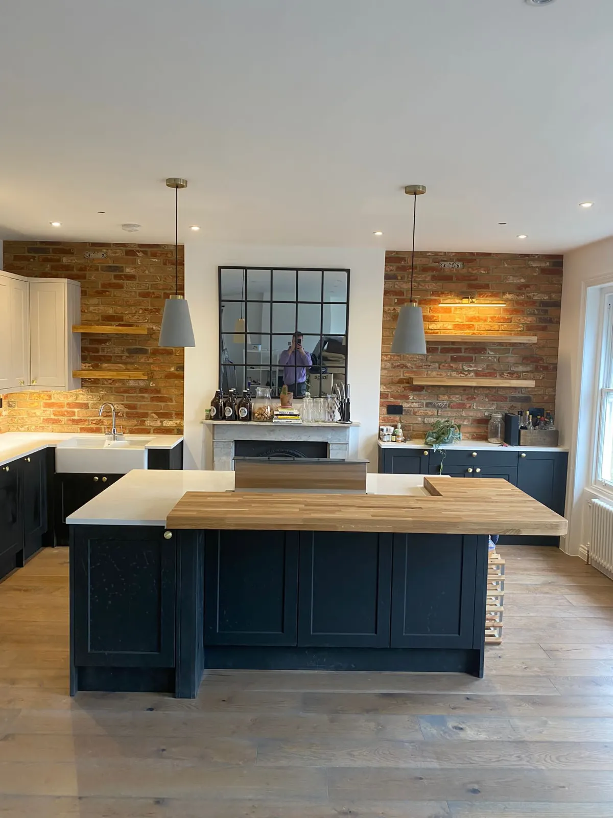 Renovated open-plan kitchen with navy island and exposed brick wall – Tenfold Renovation